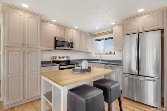 kitchen with sink, a breakfast bar area, appliances with stainless steel finishes, light hardwood / wood-style floors, and a kitchen island