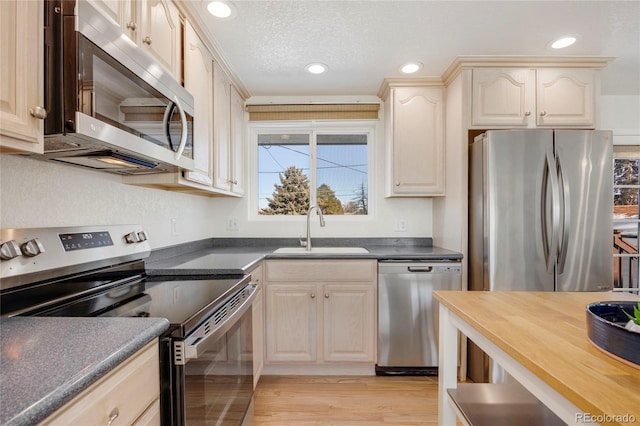 kitchen with wood counters, sink, a textured ceiling, light wood-type flooring, and stainless steel appliances