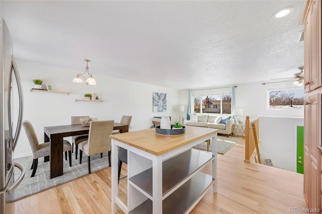 dining area featuring ceiling fan, a textured ceiling, and light wood-type flooring