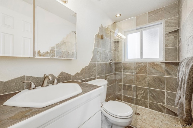 bathroom with vanity, a tile shower, and toilet