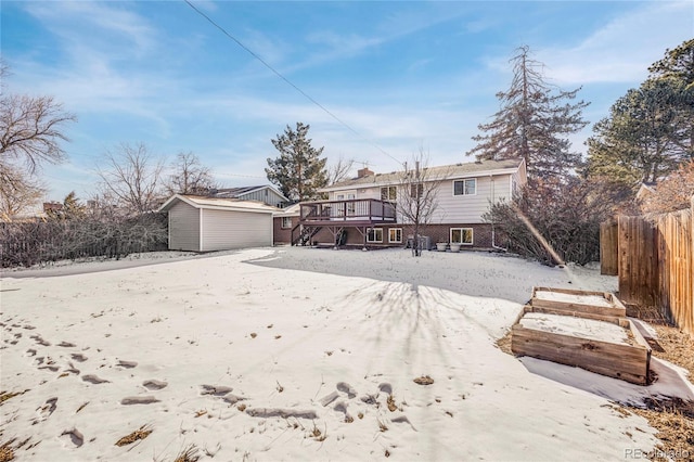 snow covered house with a wooden deck and a shed