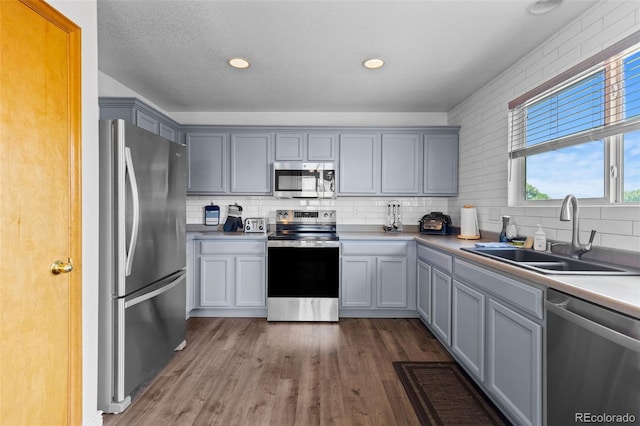 2430 E 109th Dr, Northglenn, CO 80233 - kitchen featuring appliances with stainless steel finishes, tasteful backsplash, wood finished floors, gray cabinets, and recessed lighting