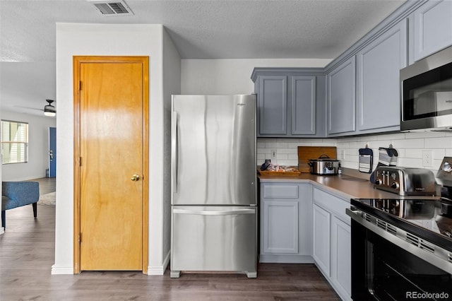 2430 E 109th Dr, Northglenn, CO 80233 - kitchen with stainless steel appliances, backsplash, wood finished floors, a ceiling fan, and gray cabinets