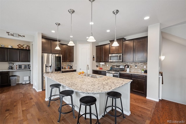 19760 W 59th Dr, Golden, CO 80403 - kitchen with stainless steel appliances, dark brown cabinets, a breakfast bar area, decorative backsplash, and a center island with sink