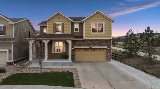 19760 W 59th Dr, Golden, CO 80403 - view of front of house featuring covered porch, an attached garage, driveway, and stone siding