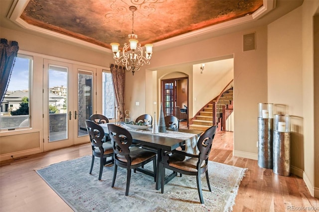 dining area featuring light hardwood / wood-style flooring, a raised ceiling, and plenty of natural light