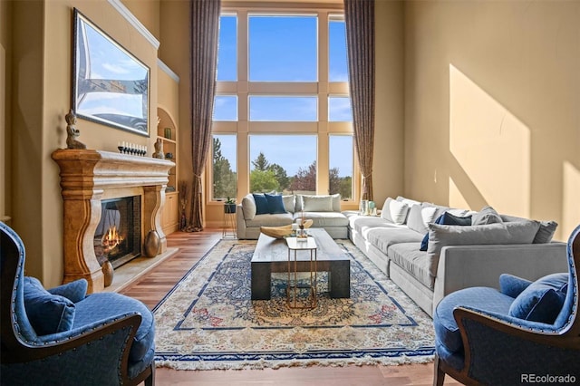 living room featuring a towering ceiling, a premium fireplace, and light hardwood / wood-style floors