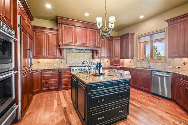 kitchen featuring decorative backsplash, light hardwood / wood-style flooring, an island with sink, and stainless steel appliances