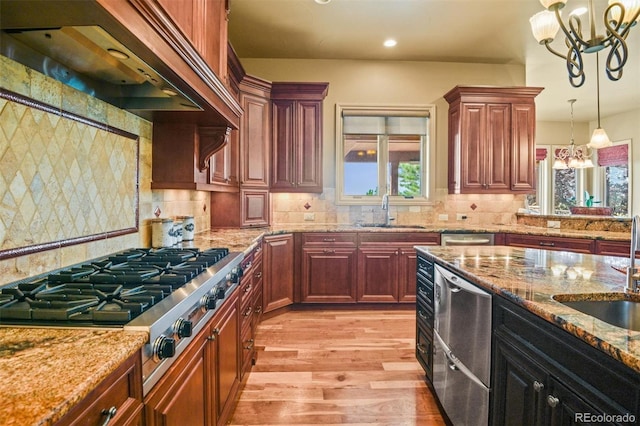 kitchen with appliances with stainless steel finishes, tasteful backsplash, light wood-type flooring, and a chandelier