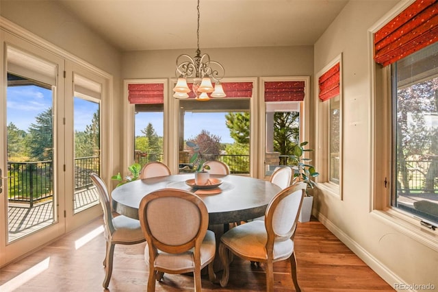 dining area with a wealth of natural light, a chandelier, and hardwood / wood-style flooring