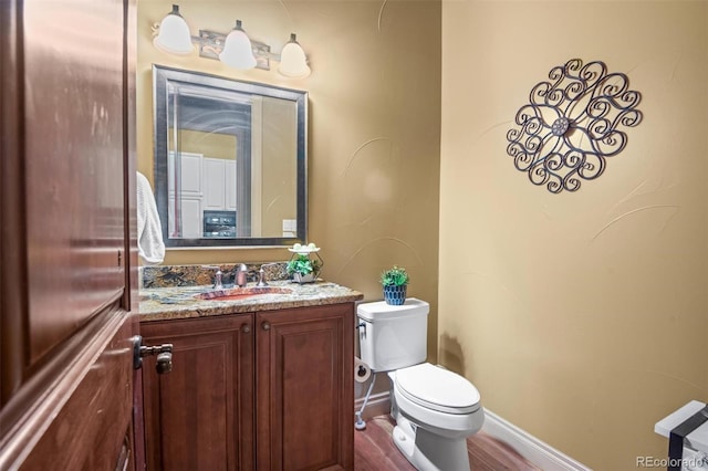 bathroom featuring wood-type flooring, vanity, and toilet