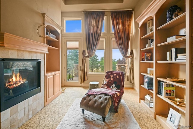 sitting room featuring light carpet, built in features, and a tile fireplace