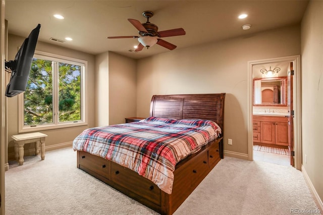 bedroom featuring ceiling fan, ensuite bath, light colored carpet, and sink