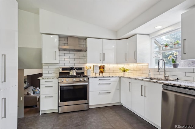 10909 W 65th Way, Arvada, CO 80004 - kitchen featuring stainless steel appliances, wall chimney range hood, a sink, modern cabinets, and vaulted ceiling