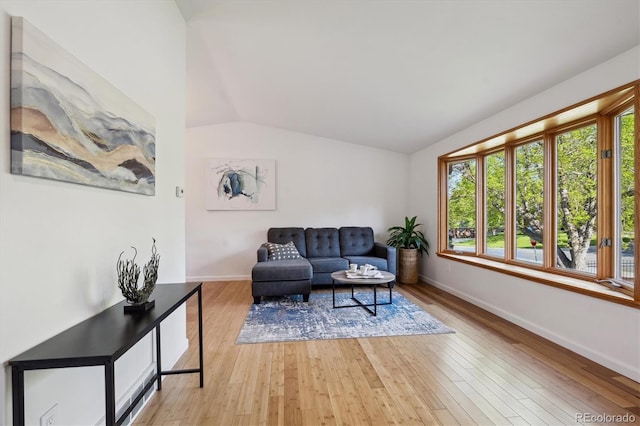10909 W 65th Way, Arvada, CO 80004 - living area with healthy amount of natural light, vaulted ceiling, baseboards, and light wood finished floors