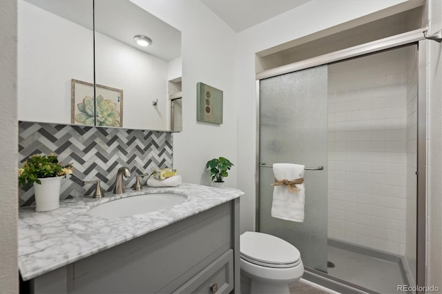 10909 W 65th Way, Arvada, CO 80004 - bathroom with a shower stall, vanity, decorative backsplash, and toilet