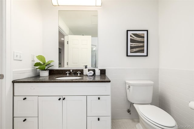 bathroom with tile patterned floors, tile walls, toilet, and vanity