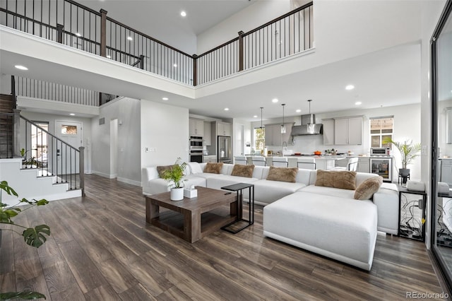 living room featuring dark hardwood / wood-style flooring, a wealth of natural light, a high ceiling, and beverage cooler