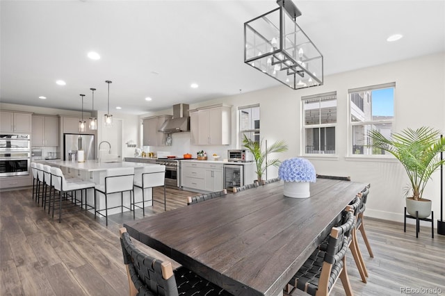 dining area featuring beverage cooler, hardwood / wood-style floors, a notable chandelier, and sink