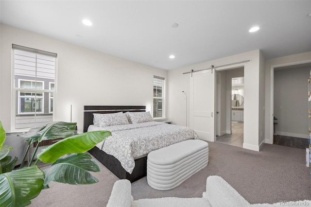 bedroom with light colored carpet and a barn door