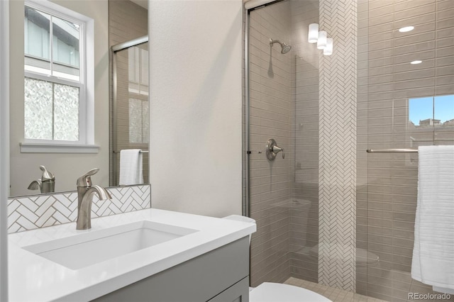 bathroom featuring vanity, toilet, a wealth of natural light, and walk in shower