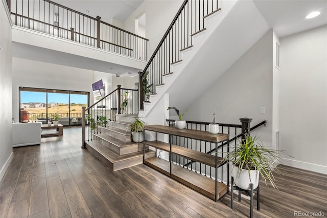 stairs featuring wood-type flooring and a high ceiling