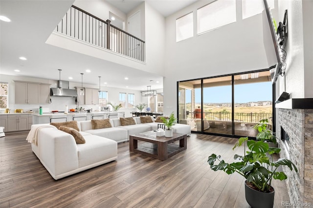 living room with a towering ceiling, hardwood / wood-style floors, a brick fireplace, and sink