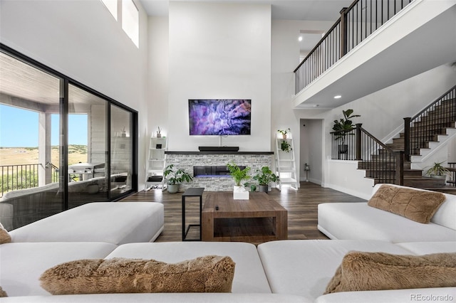 living room featuring a towering ceiling, hardwood / wood-style floors, and a stone fireplace