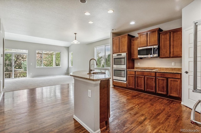 kitchen featuring dark colored carpet, sink, decorative light fixtures, a textured ceiling, and stainless steel appliances