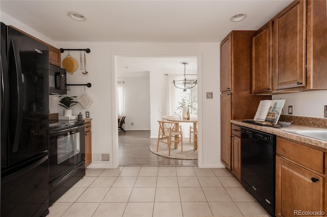 916 Florence St, Aurora, CO 80010 - kitchen with black appliances, brown cabinetry, light tile patterned floors, a chandelier, and recessed lighting