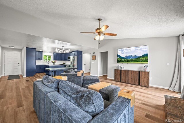 3881 S Bahama St, Aurora, CO 80013 - living area with a chandelier, baseboards, a textured ceiling, a ceiling fan, and light wood finished floors