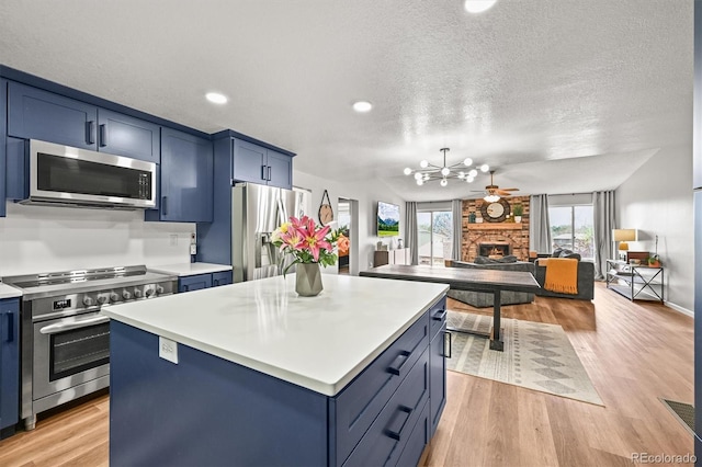 3881 S Bahama St, Aurora, CO 80013 - kitchen with stainless steel appliances, blue cabinets, light countertops, a chandelier, and a kitchen island