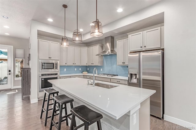5834 Beeler Ct, Denver, CO 80238 - kitchen featuring wall chimney range hood, stainless steel appliances, tasteful backsplash, a kitchen breakfast bar, and light countertops