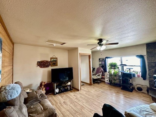 living room with light hardwood / wood-style floors, ceiling fan, and a textured ceiling