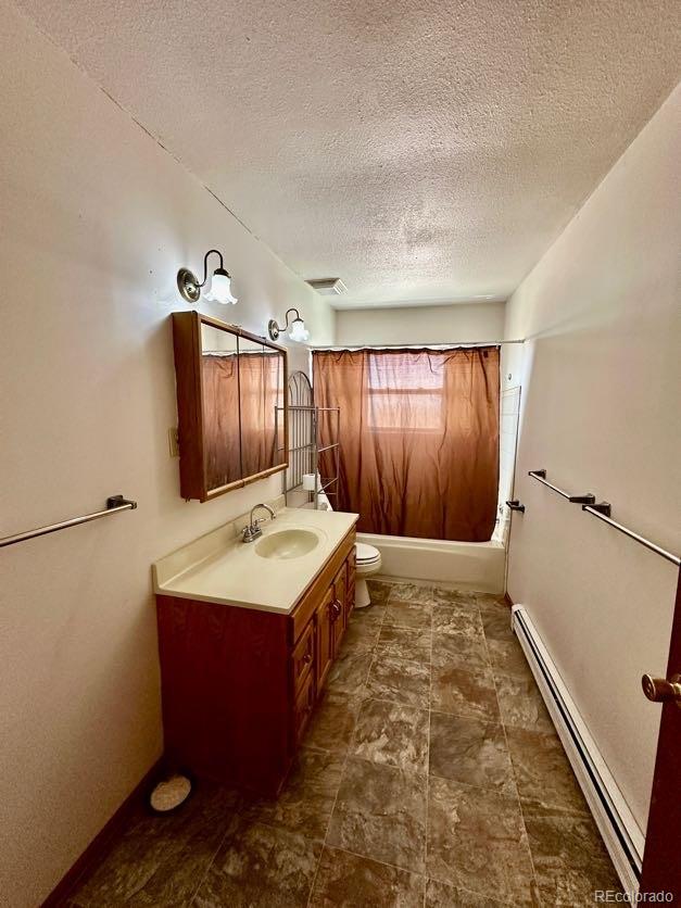 bathroom with a baseboard radiator, tile floors, large vanity, toilet, and a textured ceiling