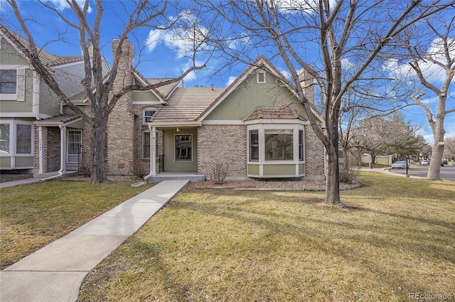 view of front of property with brick siding, a chimney, and a front yard