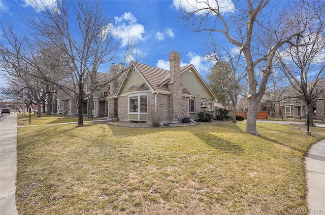 view of home's exterior with a yard, brick siding, a chimney, and a tiled roof