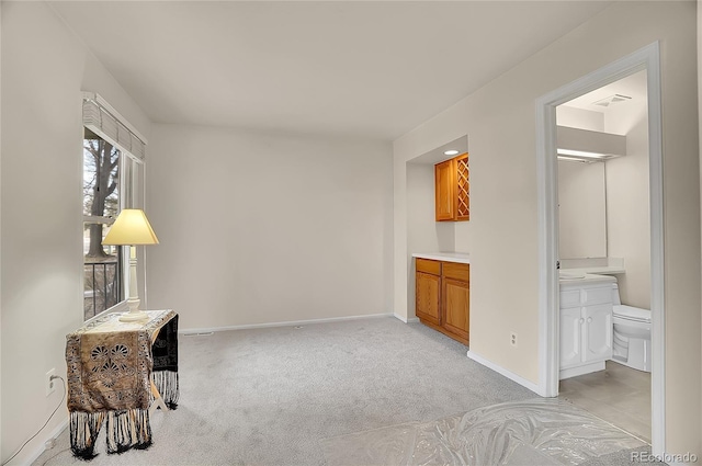 bedroom featuring light colored carpet, ensuite bath, visible vents, and baseboards