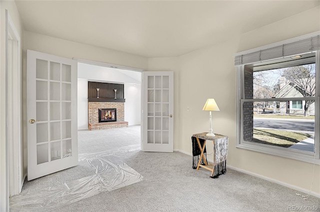 interior space featuring light carpet, french doors, a fireplace, and baseboards