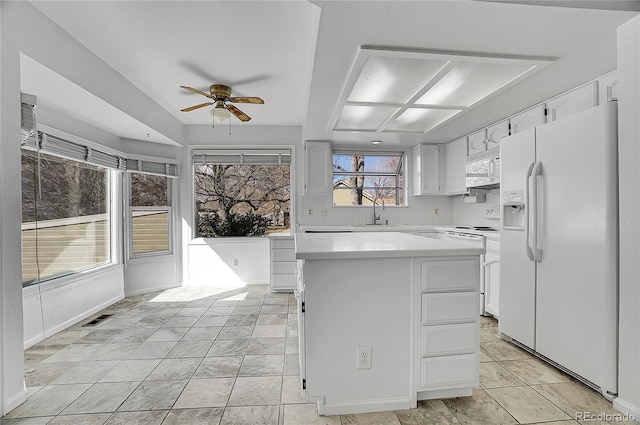 kitchen featuring white appliances, light countertops, a sink, and white cabinets