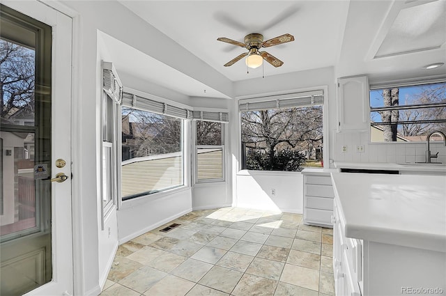 unfurnished sunroom featuring ceiling fan, visible vents, and a sink