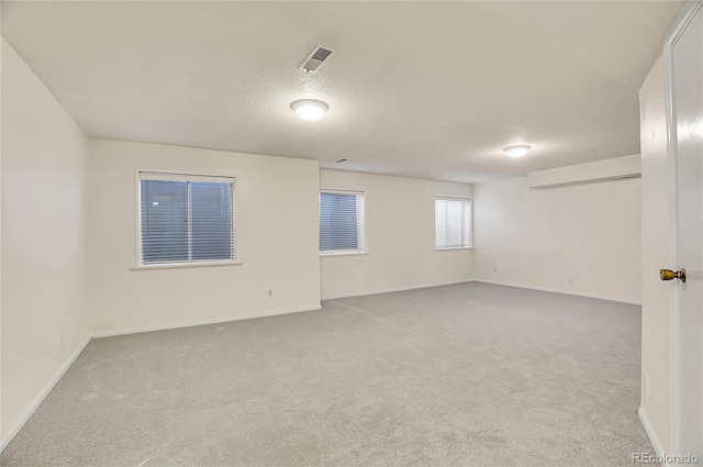 spare room with light carpet, baseboards, and visible vents