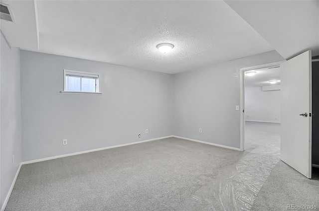 empty room featuring a textured ceiling, carpet, visible vents, and baseboards