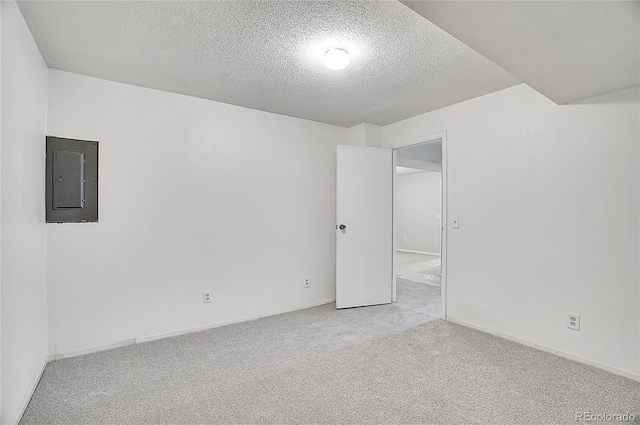 carpeted spare room with electric panel, a textured ceiling, and baseboards