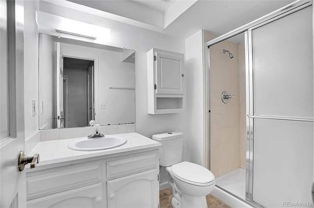 bathroom with a stall shower, vanity, and toilet