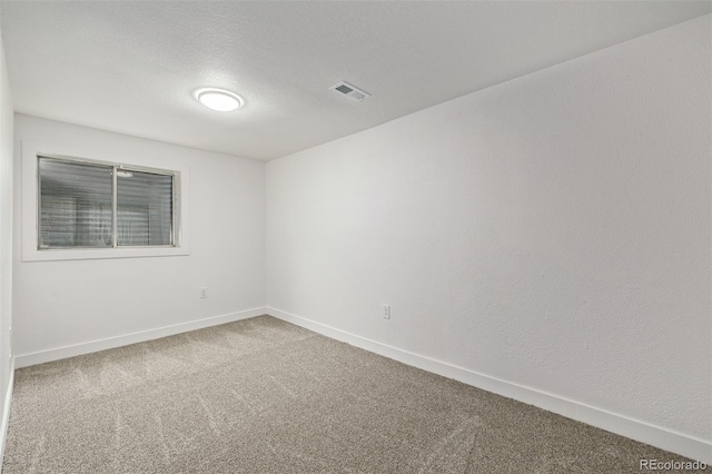 spare room with a textured ceiling, carpet floors, visible vents, and baseboards