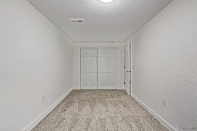 unfurnished bedroom featuring light carpet, baseboards, visible vents, and a textured ceiling