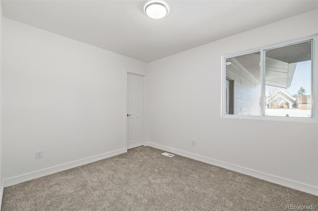 empty room featuring carpet flooring, visible vents, and baseboards