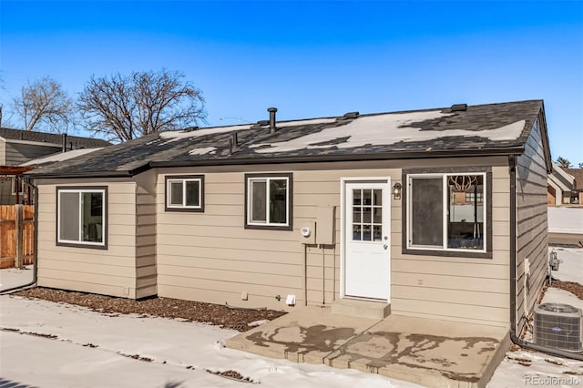 snow covered house with central AC, a patio area, and fence