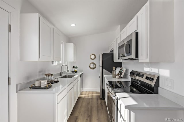 kitchen featuring dark wood finished floors, stainless steel appliances, light countertops, white cabinetry, and a sink